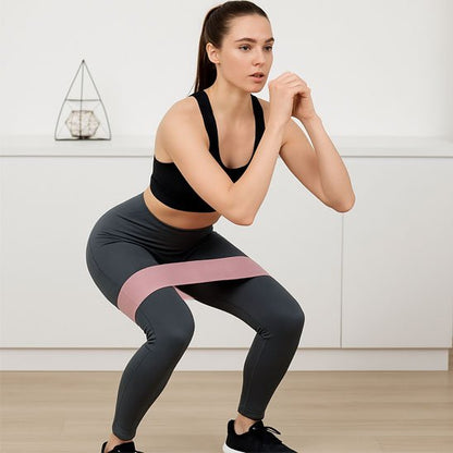 Femme en train de faire squat avec un elastique de résistance rose 20 lb placé autour des cuisses