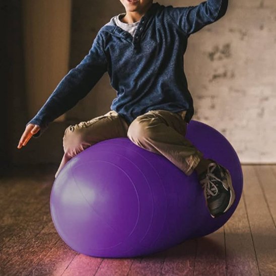 ballon de yoga cacahuète, un garçon assis sur un ballon en tenant son équilibre