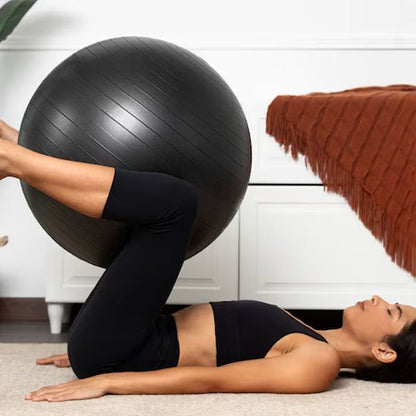 Ballon de yoga, une femme couchée sur le dos et un ballon est entre les jambes qui sont pliés dans l'air