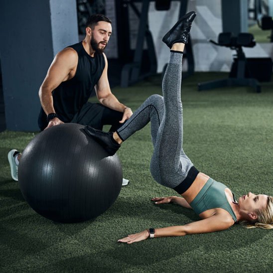 ballon de yoga une femme sur le dos un pied plié et posé sur le ballon et l'autre tendus  en haut