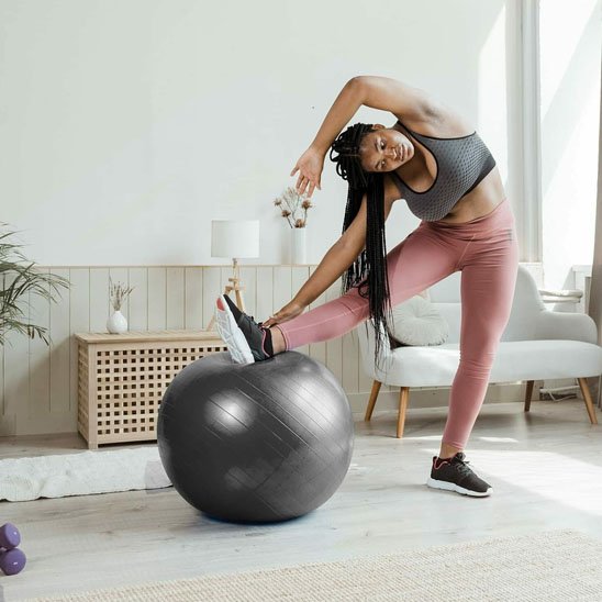 Ballon pilates, une femme pose son pied sur le ballon en gardant son équilibre