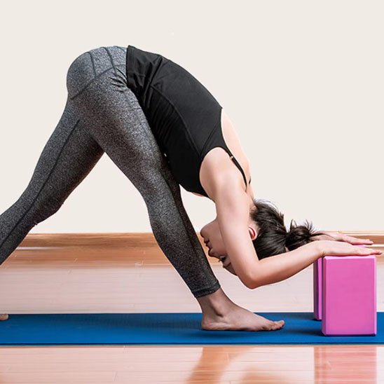 Brique yoga, femme étire ses jambes en penchant vers l'avant