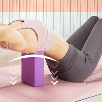 femme éttire son dos avec brique de yoga violet
