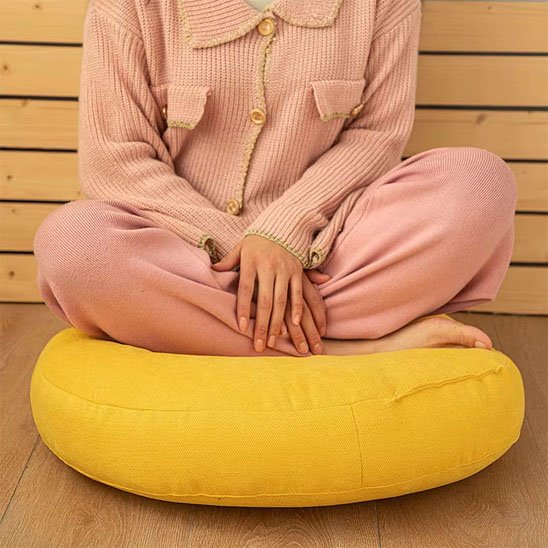 femme assise sur Zafu mains sur les jambes pliés 