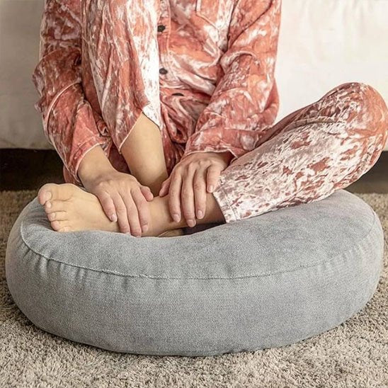 femme assise sur zafu mains sur les pieds