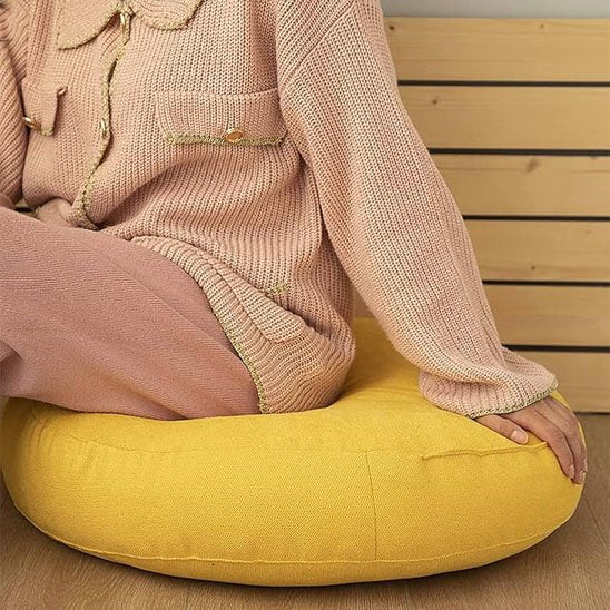 femme sur Zafu mains sur le coussin 