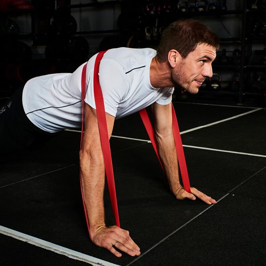 homme pratique les posh-up avec elastique musculation rouge résistance de 15 à  35 lbs