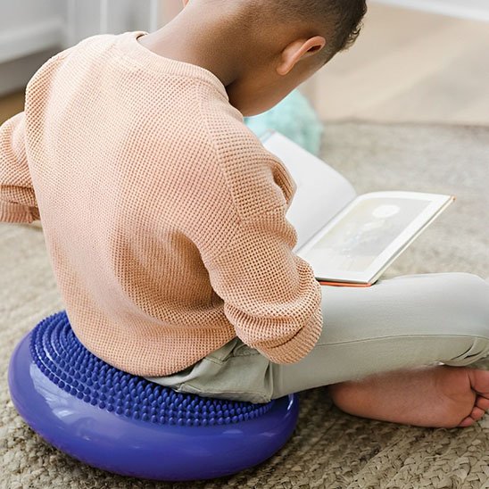un garçon assis sur Coussin yoga en faisant la lecture 
